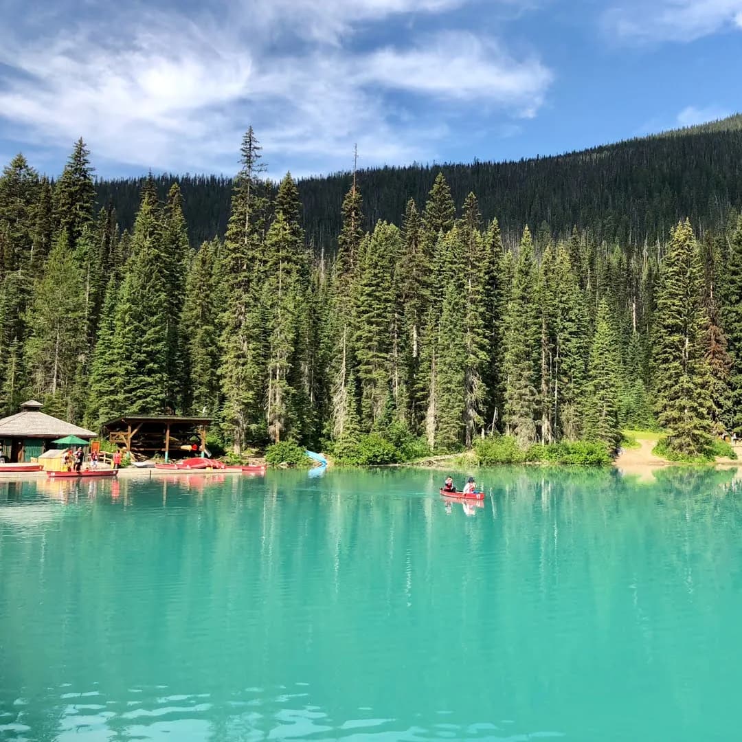 Canoa em lago turquesa cercado por floresta nas Montanhas Rochosas Canadenses