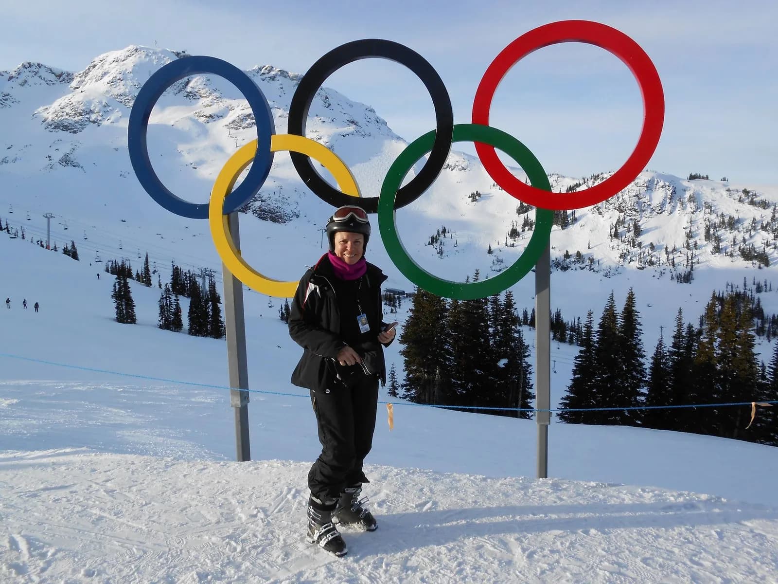 Cecilia by the Olympic Rings at the top of Whistler Blackcomb, with snow-capped mountains in the background